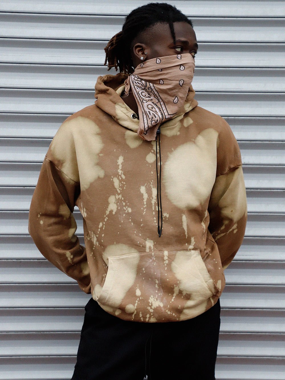 A man wearing a BURLYWOOD tie dye hoodie that fits true to size and is made of acrylic.