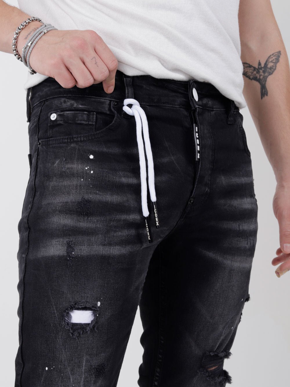 A man wearing MODERO denim jeans with ripped knees.