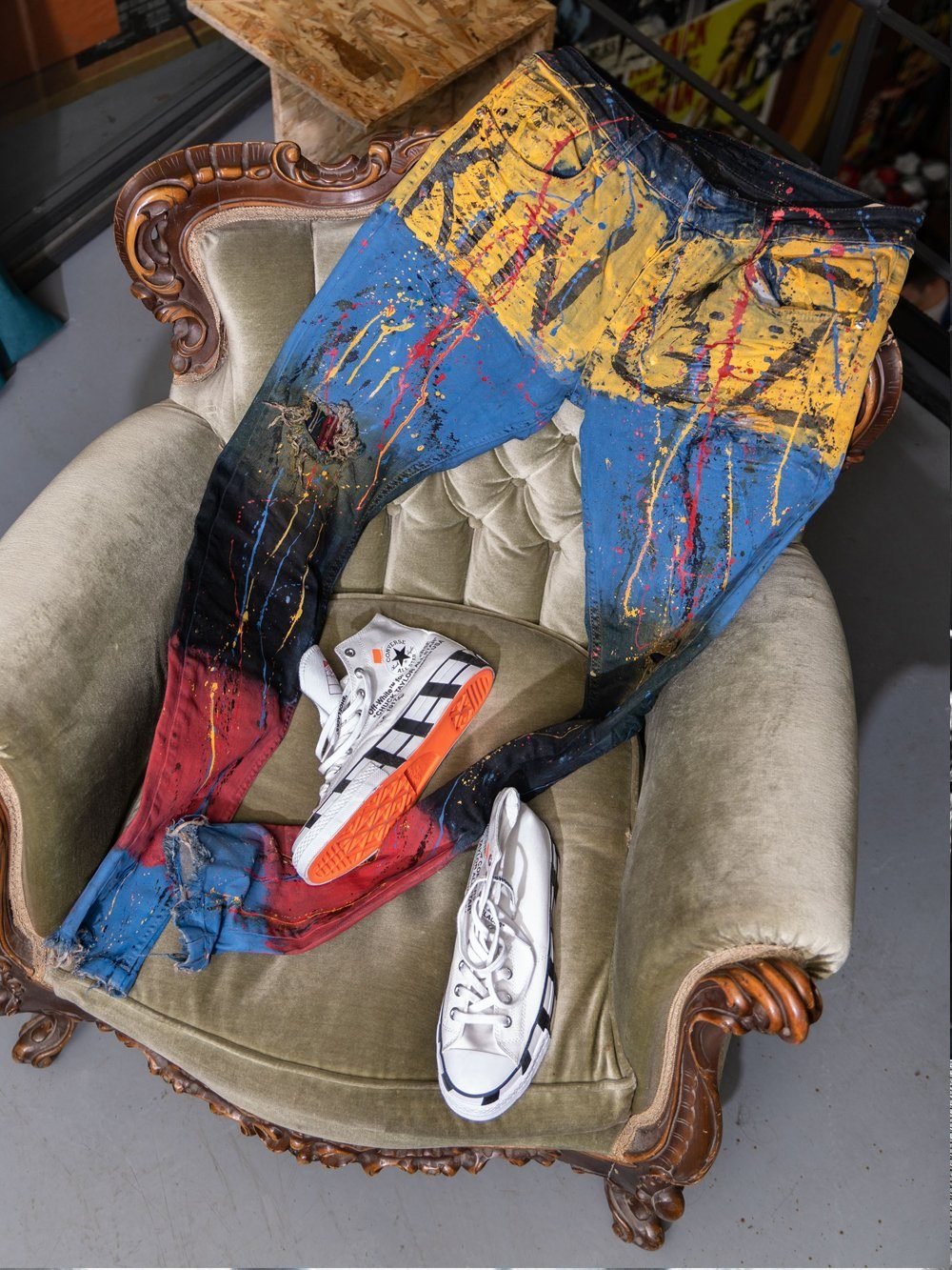A TOO MUCH and a pair of sneakers sitting on a chair.